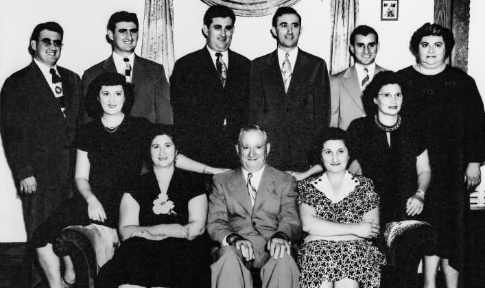The Pete Ferraro family is prominently featured on the front wall of the Gay Parita ballroom in Carona. Shown are back row left to right, Jim, Frank, Joe, Pete Jr., Mike and Minnie Parise. On sofa left to right Edith Sachetta, Pauline Ducrous, Pete Ferraro Sr., Lily Getto Annie Decicco.